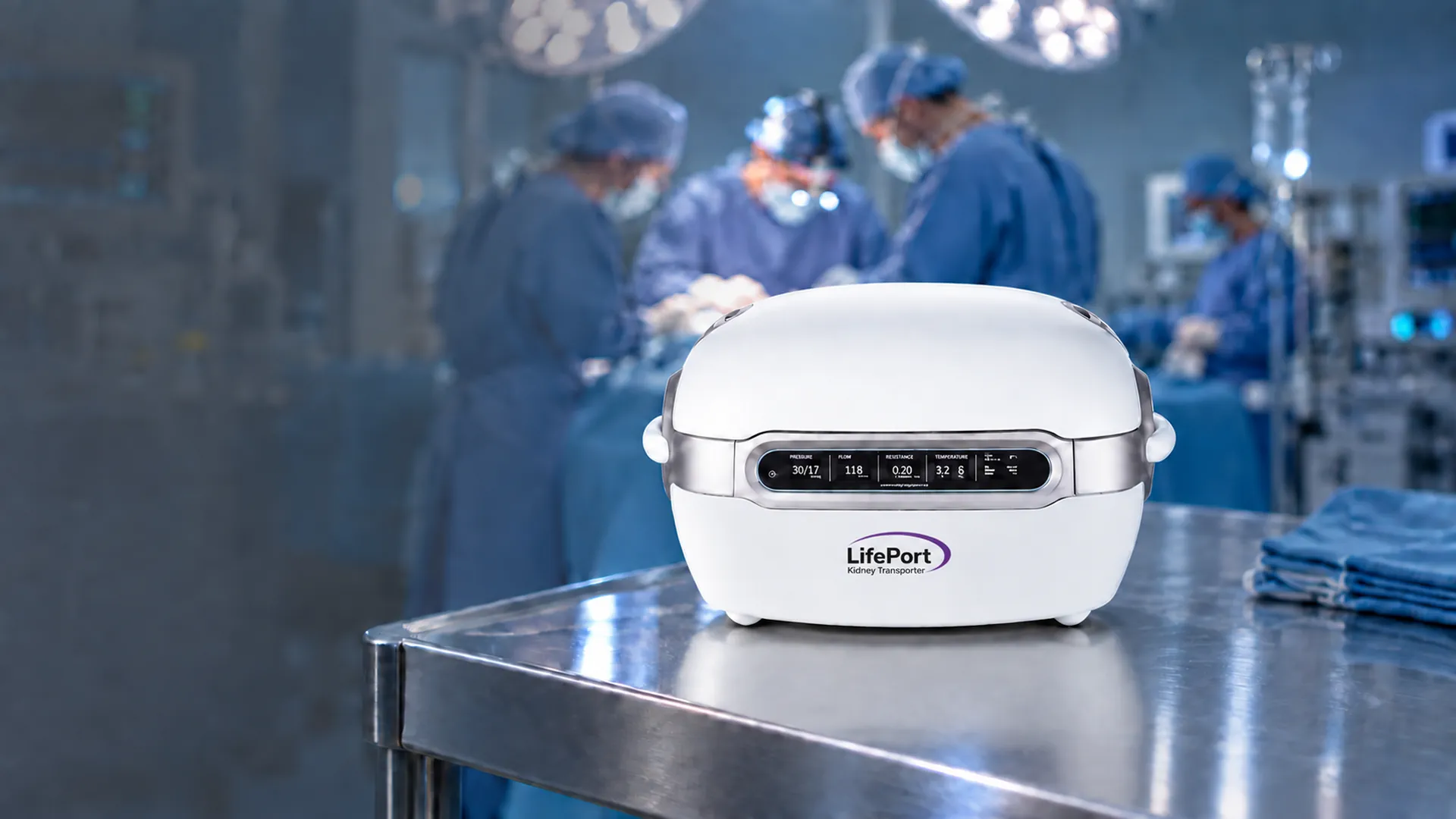 LifePort® Kidney Transporter sobre una mesa de acero en un quirófano, con el equipo quirúrgico al fondo.