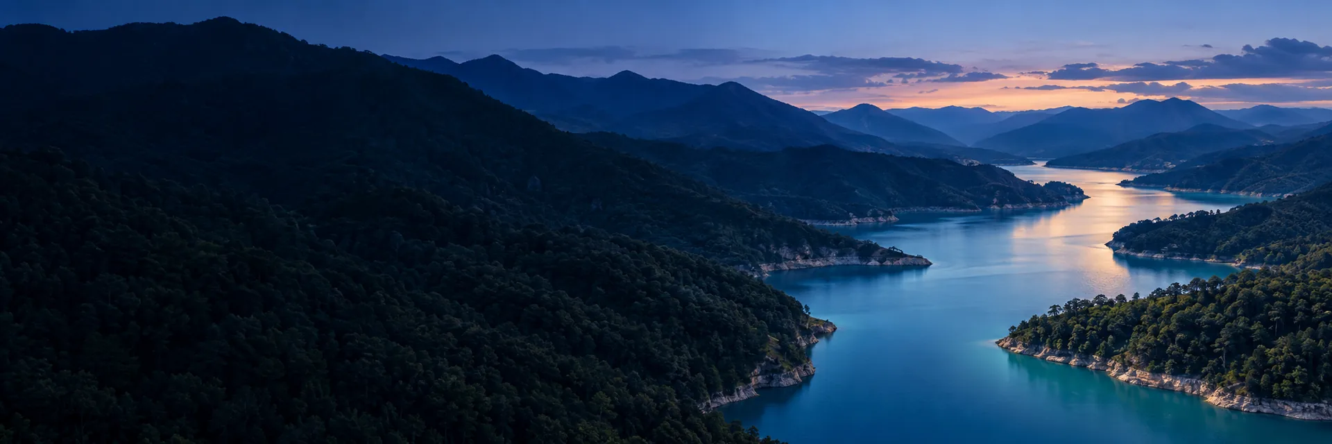 Paisaje de montañas y un río al atardecer.